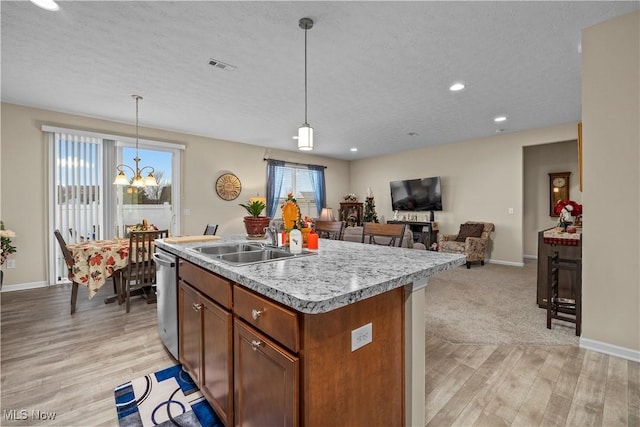 kitchen with sink, light hardwood / wood-style flooring, an island with sink, a chandelier, and decorative light fixtures