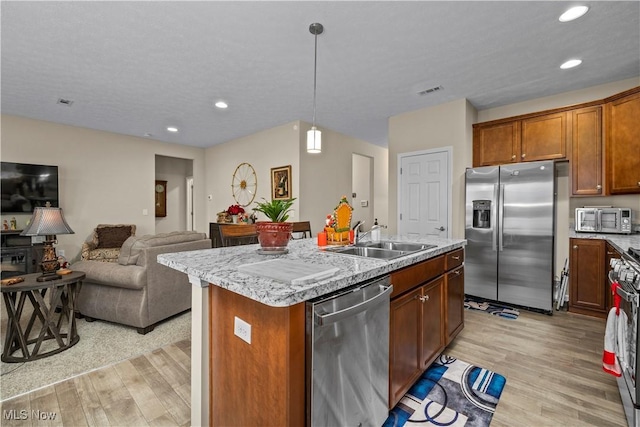 kitchen featuring sink, an island with sink, stainless steel appliances, and light wood-type flooring