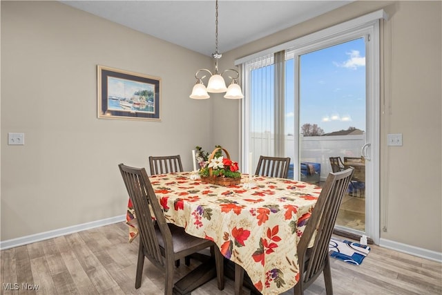 dining space with light hardwood / wood-style floors and a chandelier