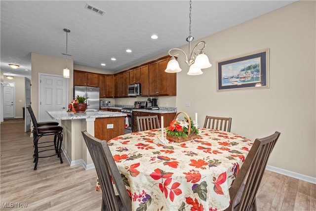 dining area featuring light hardwood / wood-style floors and a notable chandelier