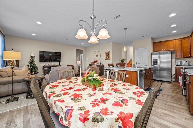 dining room featuring sink, light hardwood / wood-style floors, and an inviting chandelier