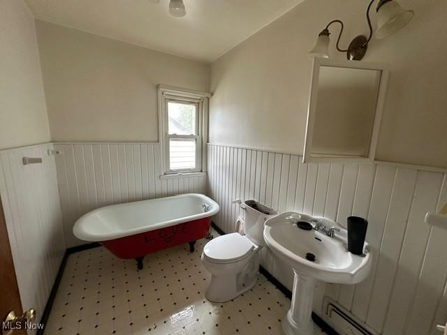 bathroom featuring toilet, sink, a tub, and a baseboard radiator