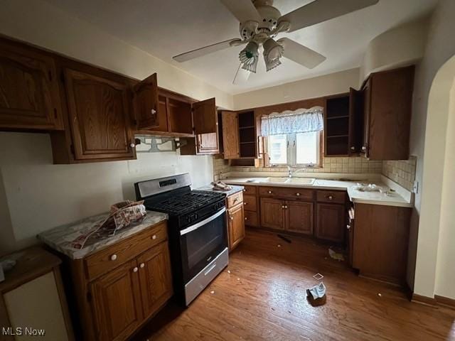 kitchen with sink, stainless steel gas range, ceiling fan, tasteful backsplash, and dark hardwood / wood-style flooring