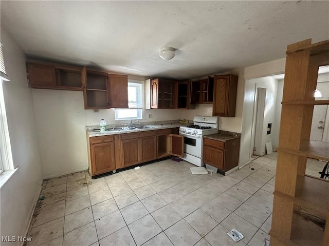 kitchen with sink, light tile patterned floors, and white range with gas stovetop