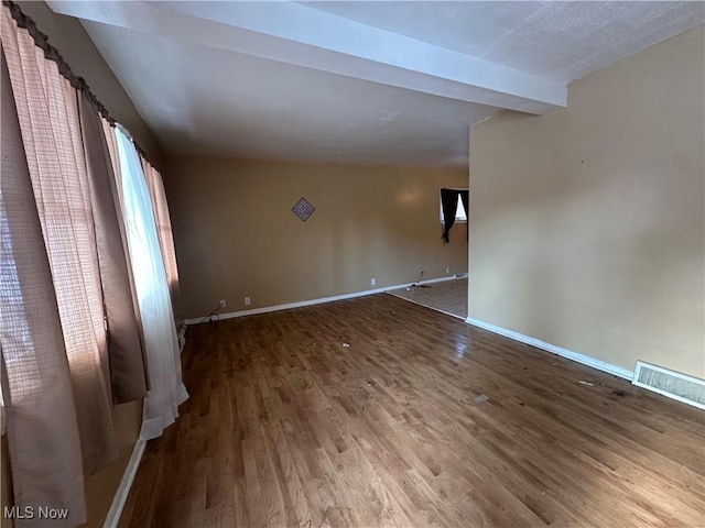 spare room with hardwood / wood-style floors and beamed ceiling