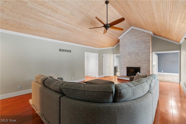 living room with hardwood / wood-style flooring, a stone fireplace, and wood ceiling