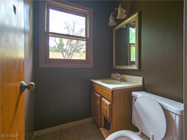 bathroom with tile patterned flooring, vanity, toilet, and a wealth of natural light