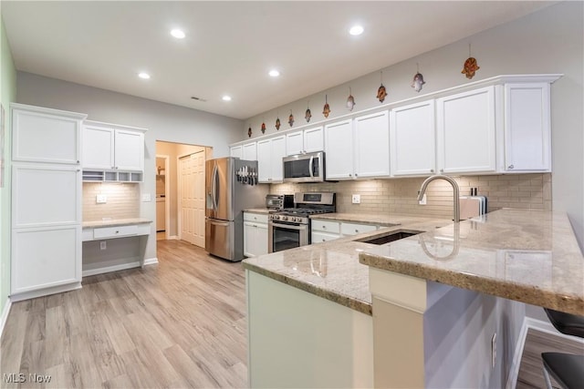 kitchen with white cabinetry, kitchen peninsula, sink, and appliances with stainless steel finishes