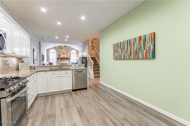 kitchen featuring kitchen peninsula, stainless steel appliances, sink, light hardwood / wood-style floors, and white cabinetry