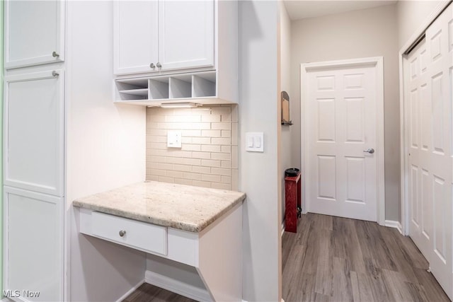 kitchen featuring decorative backsplash, light hardwood / wood-style floors, white cabinetry, and light stone countertops