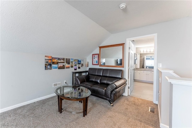 living room featuring a textured ceiling, light colored carpet, and lofted ceiling