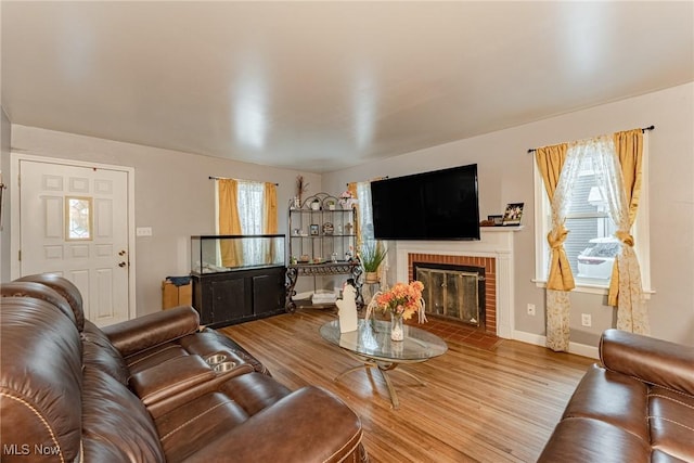 living room with hardwood / wood-style floors, a healthy amount of sunlight, and a brick fireplace