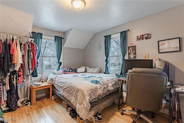 bedroom with light hardwood / wood-style floors, multiple windows, and lofted ceiling