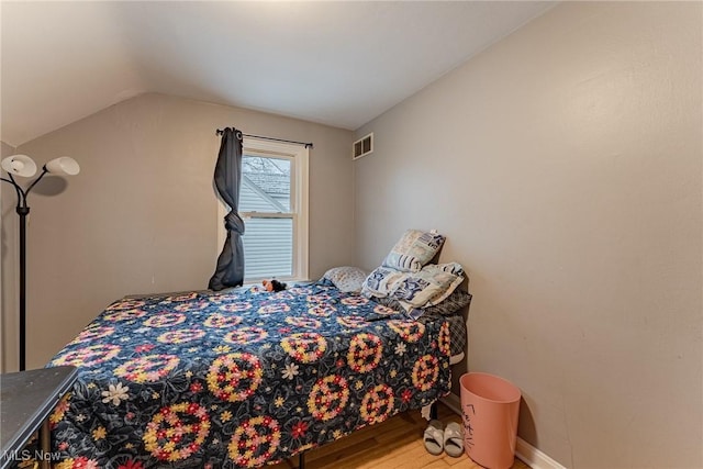 bedroom with vaulted ceiling and hardwood / wood-style flooring