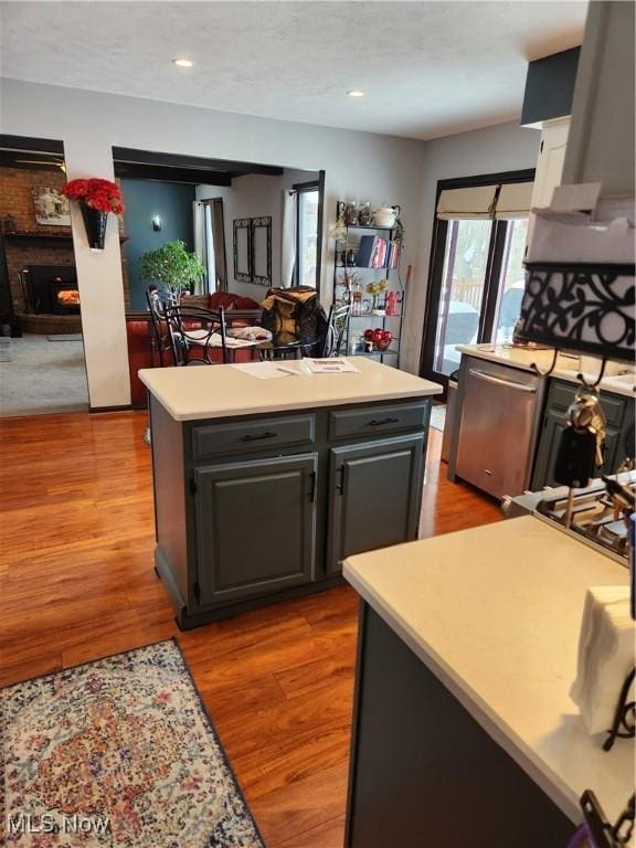 kitchen with gray cabinetry, ventilation hood, light wood-type flooring, dishwasher, and a kitchen island