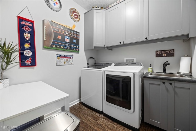 laundry room with a textured ceiling, washer and clothes dryer, cabinets, dark wood-type flooring, and sink