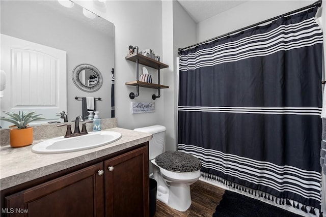 bathroom with toilet, wood-type flooring, and vanity