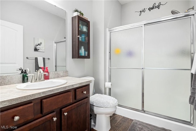 bathroom featuring a shower with shower door, hardwood / wood-style floors, toilet, and vanity