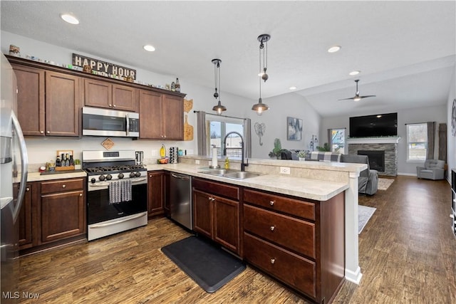 kitchen featuring stainless steel appliances, kitchen peninsula, hanging light fixtures, and sink