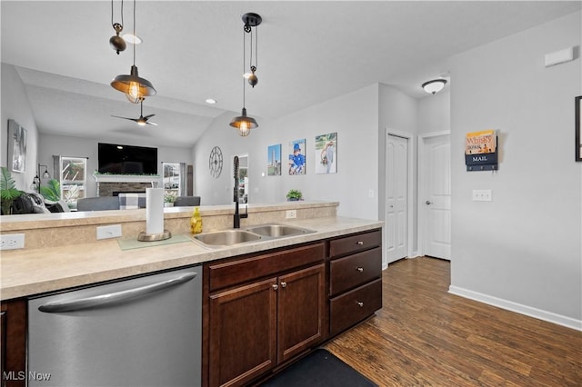 kitchen with decorative light fixtures, dark wood-type flooring, a stone fireplace, sink, and stainless steel dishwasher