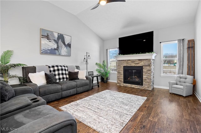 living room with ceiling fan, dark wood-type flooring, lofted ceiling, and a stone fireplace