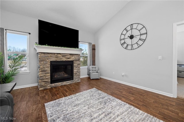 living room featuring vaulted ceiling, dark hardwood / wood-style floors, and a stone fireplace