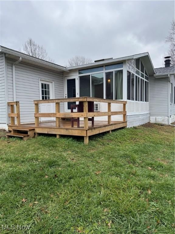 rear view of property featuring a sunroom, a deck, and a lawn