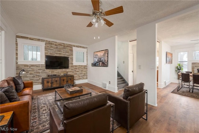 living room with ceiling fan, a textured ceiling, and hardwood / wood-style flooring