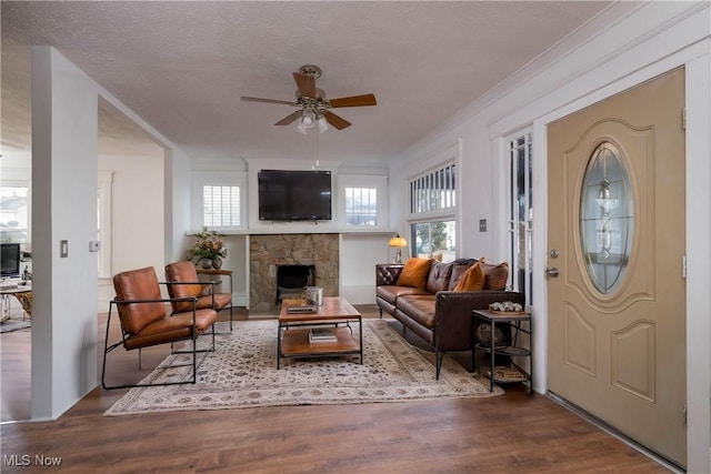 living room with hardwood / wood-style floors, a textured ceiling, ceiling fan, and ornamental molding