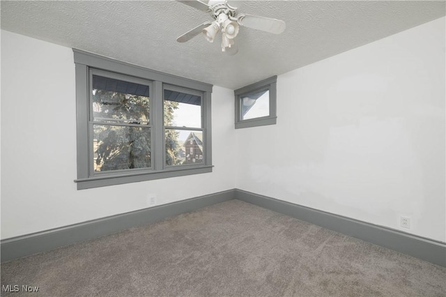 empty room featuring ceiling fan, carpet floors, and a textured ceiling