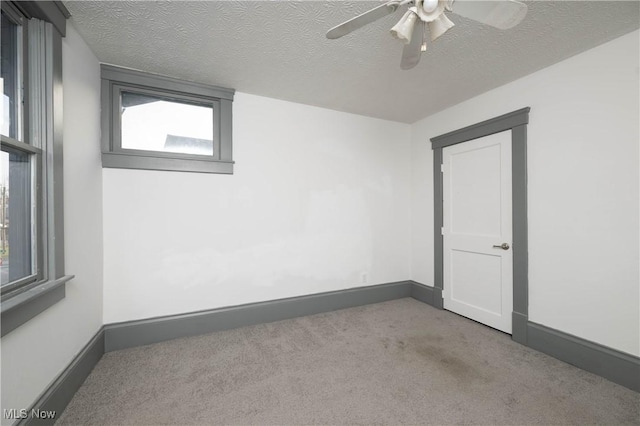 carpeted empty room featuring a textured ceiling and ceiling fan