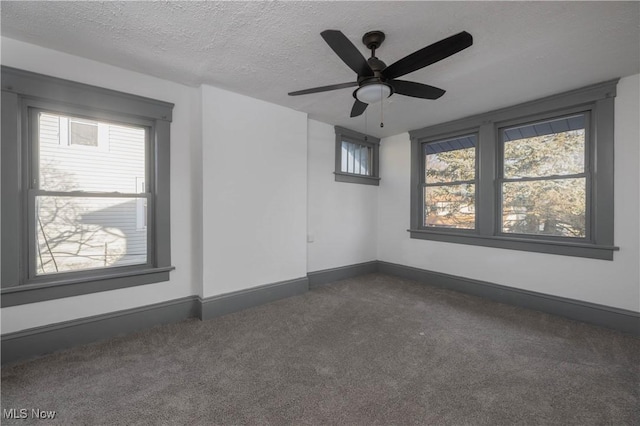 unfurnished room with dark colored carpet, ceiling fan, and a textured ceiling