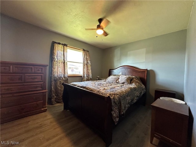 bedroom with dark hardwood / wood-style flooring and ceiling fan