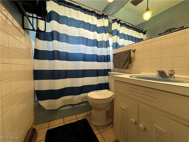 bathroom with walk in shower, toilet, tile walls, vanity, and tile patterned flooring