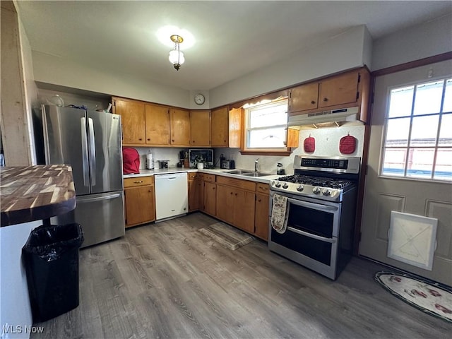 kitchen with stainless steel appliances, sink, backsplash, and light hardwood / wood-style floors