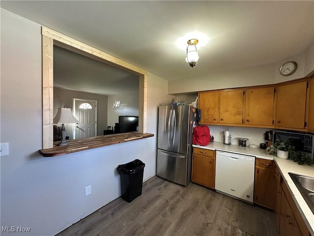 kitchen with hardwood / wood-style flooring, white dishwasher, and stainless steel refrigerator