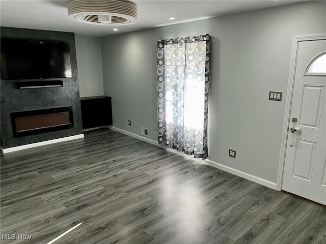 unfurnished living room featuring dark hardwood / wood-style flooring and a large fireplace