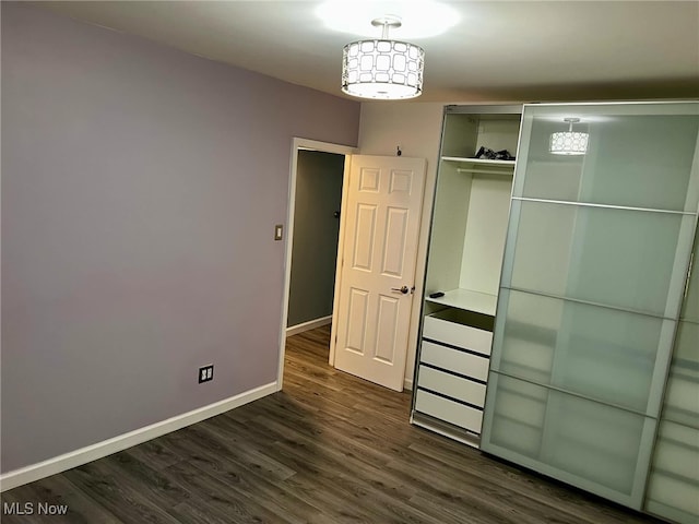 unfurnished bedroom with a closet and dark wood-type flooring