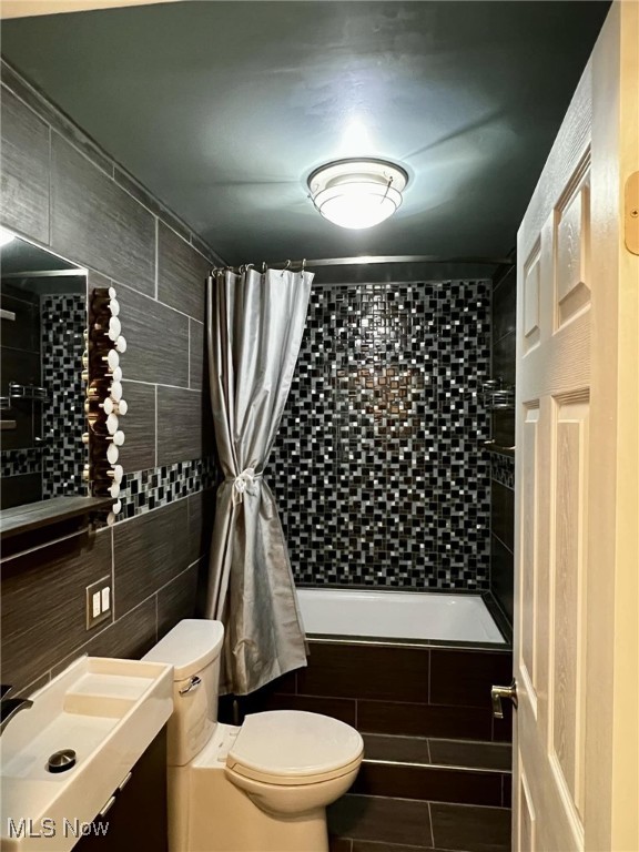 full bathroom featuring vanity, toilet, tile walls, and shower / tub combo with curtain