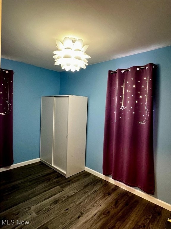 unfurnished bedroom featuring a closet, dark hardwood / wood-style flooring, and an inviting chandelier