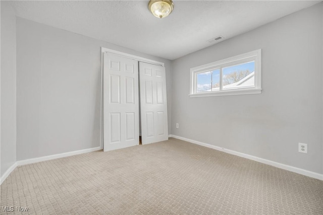 unfurnished bedroom featuring a closet, carpet flooring, visible vents, and baseboards