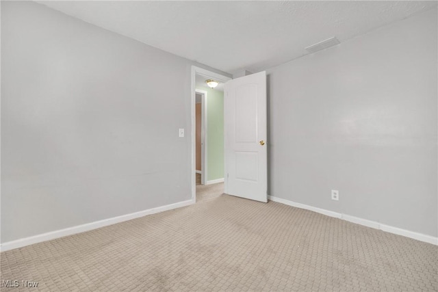 empty room featuring light colored carpet and baseboards