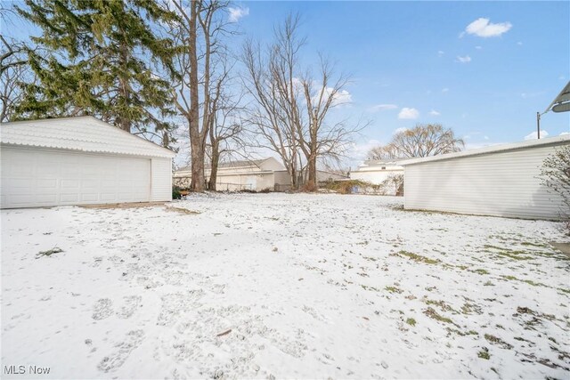 yard layered in snow with a garage and an outbuilding