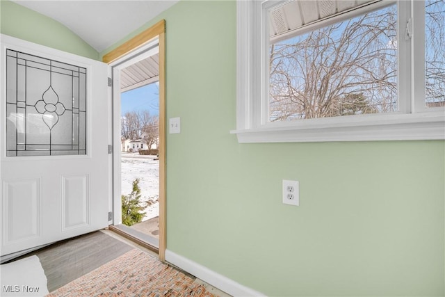 entryway featuring a wealth of natural light, baseboards, wood finished floors, and vaulted ceiling