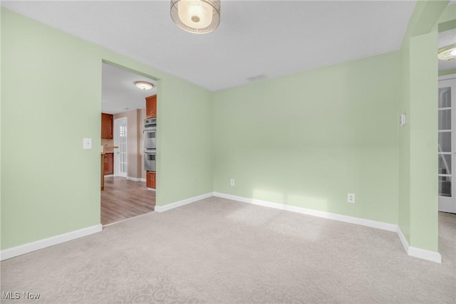 empty room featuring light carpet and baseboards