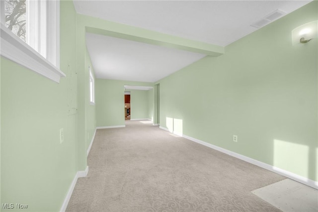 carpeted spare room with beamed ceiling, visible vents, and baseboards