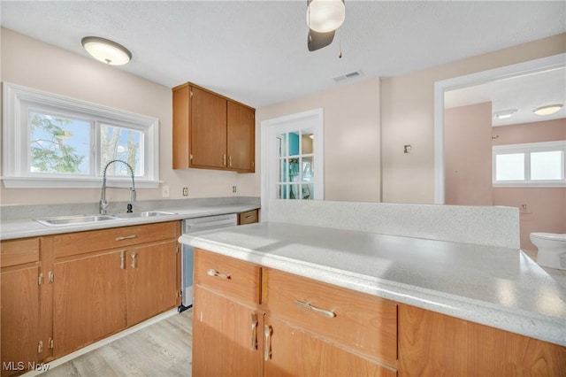 kitchen with light wood finished floors, visible vents, dishwasher, light countertops, and a sink