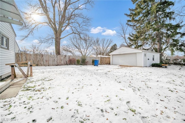 snowy yard with an outdoor structure, fence, and a garage