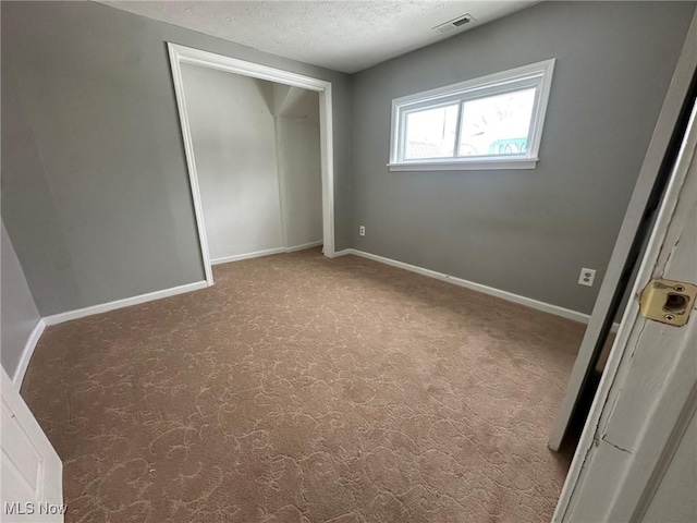 unfurnished bedroom with visible vents, baseboards, carpet floors, a closet, and a textured ceiling