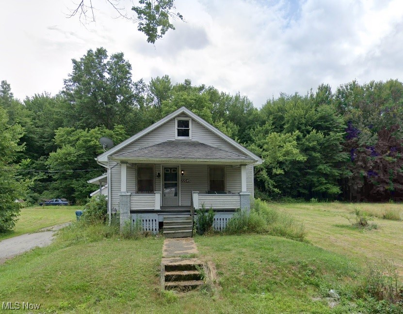 bungalow with a porch and a front lawn